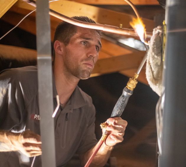  A Paragon Service Pros worker diligently fixes a pipe within a house, demonstrating expertise in home maintenance.