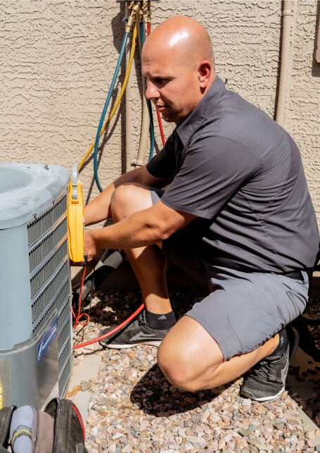 A technician from Paragon Service Pros repairs an air conditioner, demonstrating expertise in HVAC maintenance.