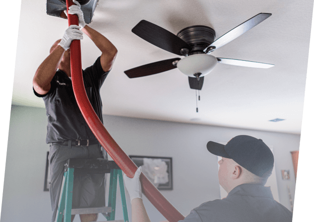 Two technicians from Paragon Service Pros install a ceiling fan in a residential setting, ensuring proper functionality.