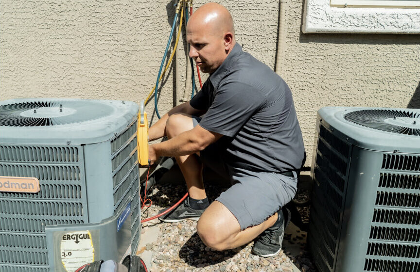 Experienced HVAC technician in Mesa adjusting settings on an outdoor air conditioning unit, improving system functionality and airflow for reliable cooling.