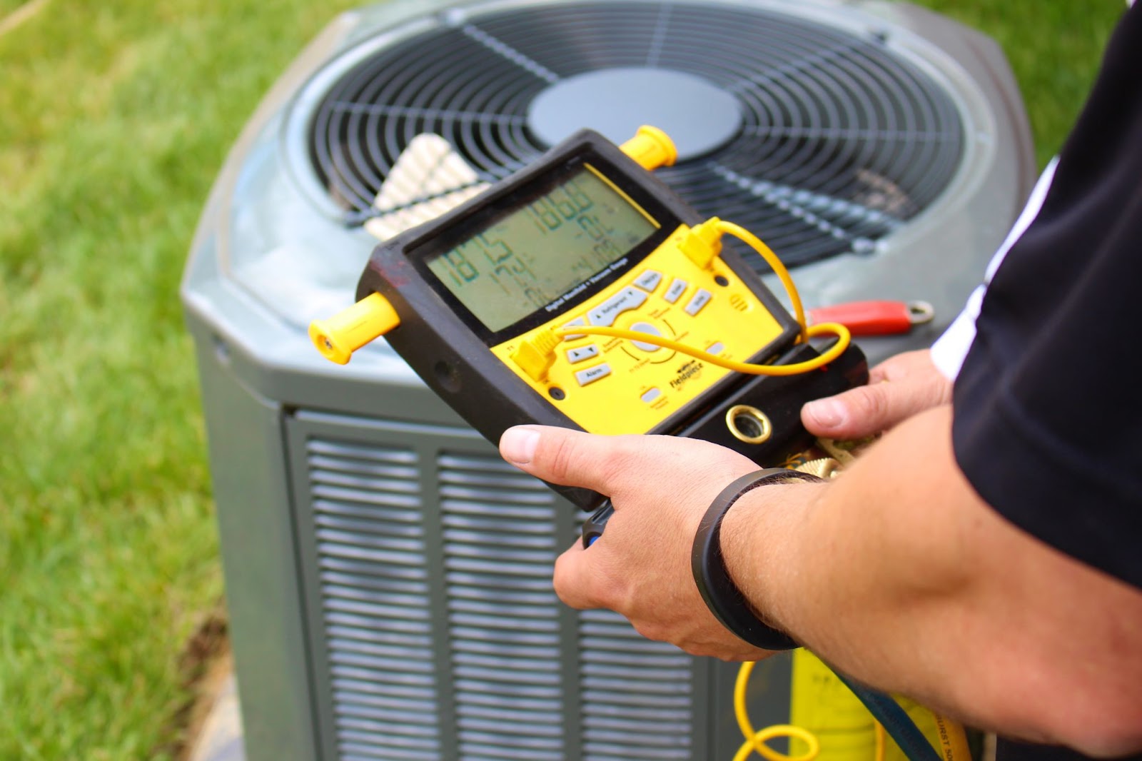 A man checks an air conditioner's temperature with a digital thermometer during HVAC maintenance services.