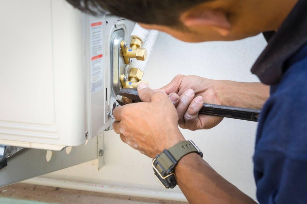 A man is repairing a water heater, focused on ensuring it functions properly and efficiently